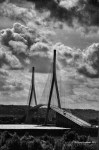 Black and white photograph of a modern cable-stayed bridge with tall pylons and dramatic clouds in the background.