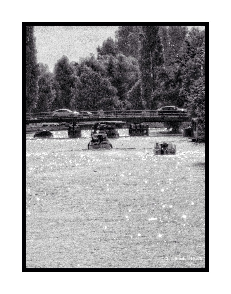 A scenic view of a canal on a warm summer day, featuring traffic jams with vehicles on a nearby bridge and boats navigating the water.