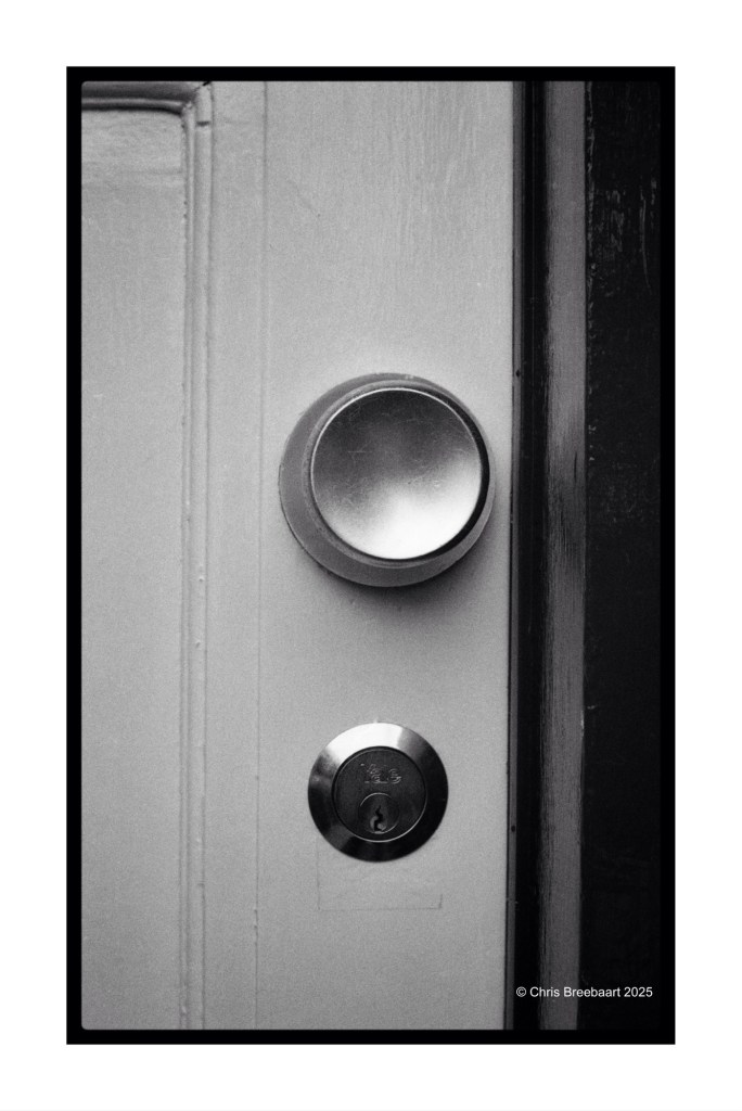 Close-up of a door handle and keyhole on a white door, featuring a circular knob and a round lock.