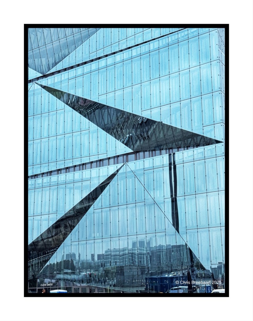 Close-up view of the Cube building in Berlin, showcasing its angular glass facade and reflections.