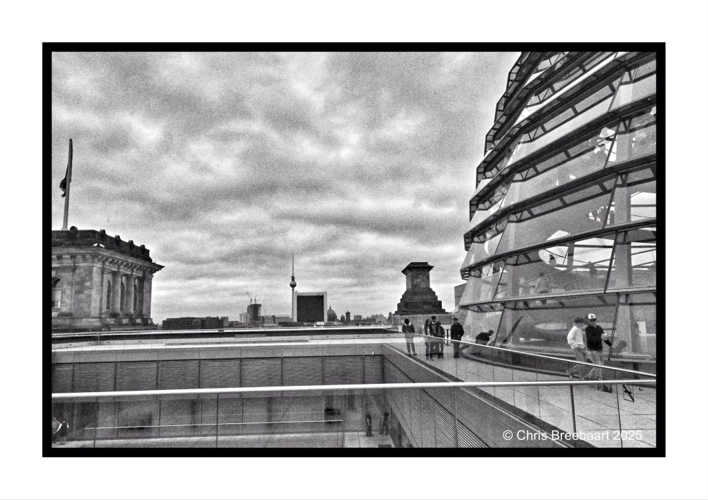 Monochrome view from the Reichstag dome in Berlin, showcasing the iconic architecture and city skyline, with visitors exploring the rooftop.