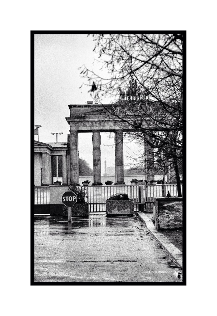 Black and white photograph of the Brandenburg Gate in Berlin, featuring a stop sign in the foreground and a foggy atmosphere.