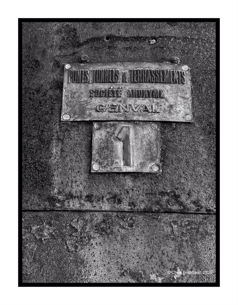 Close-up of a weathered metal plaque with inscriptions, displaying the numbers and text related to bridges, tunnels, and earthworks, mounted on a rusty background.