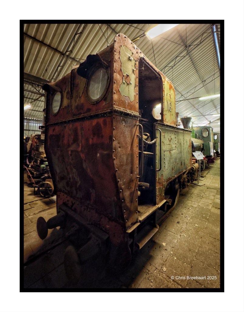 Close-up of an old, rusty steam locomotive in a museum with visible wear and tear, showcasing its historical significance.
