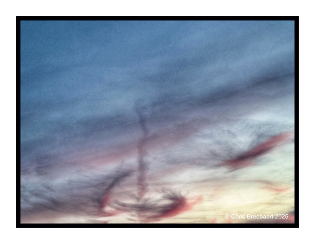 A dramatic sunset sky filled with wispy clouds, showcasing shades of blue, pink, and soft yellow.