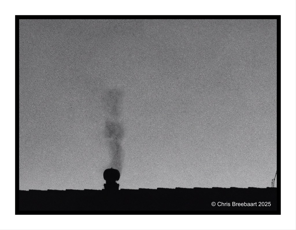 A silhouette of a chimney emitting smoke against a monochromatic background, capturing the essence of a quiet evening.