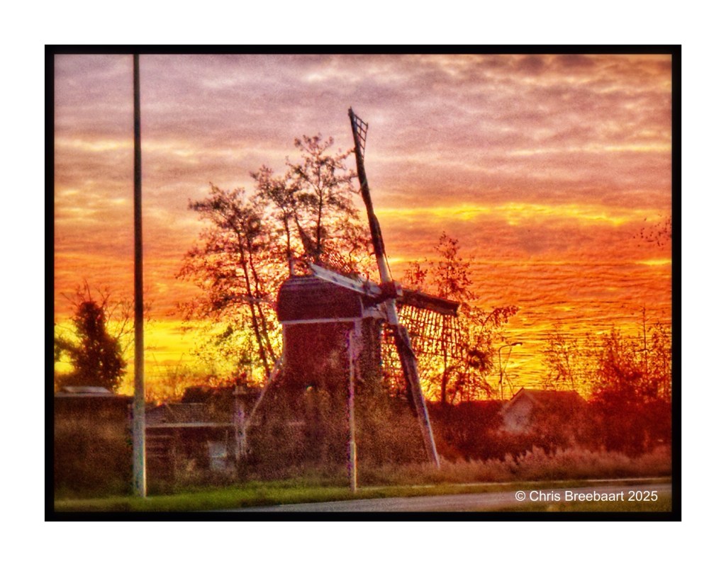 Sunrise over an Autumn landscape featuring a traditional windmill, captured from a car.