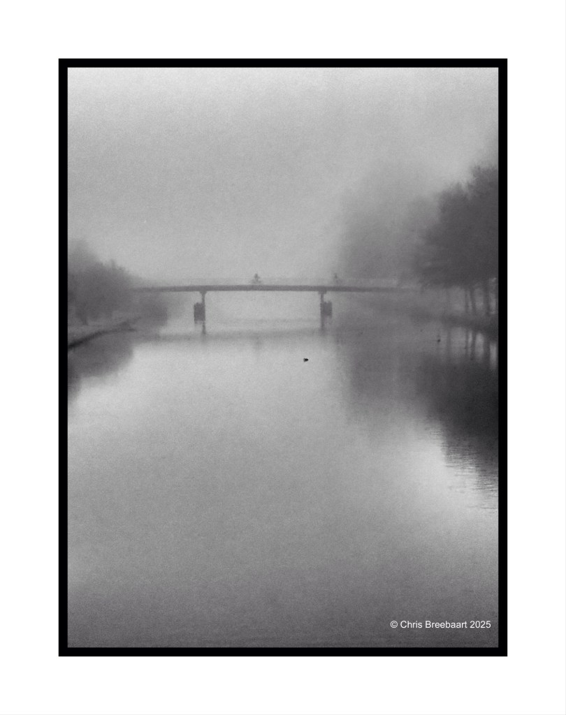 A misty river scene featuring a bridge in the background, with silhouettes of people crossing and a still water surface reflecting the fog.