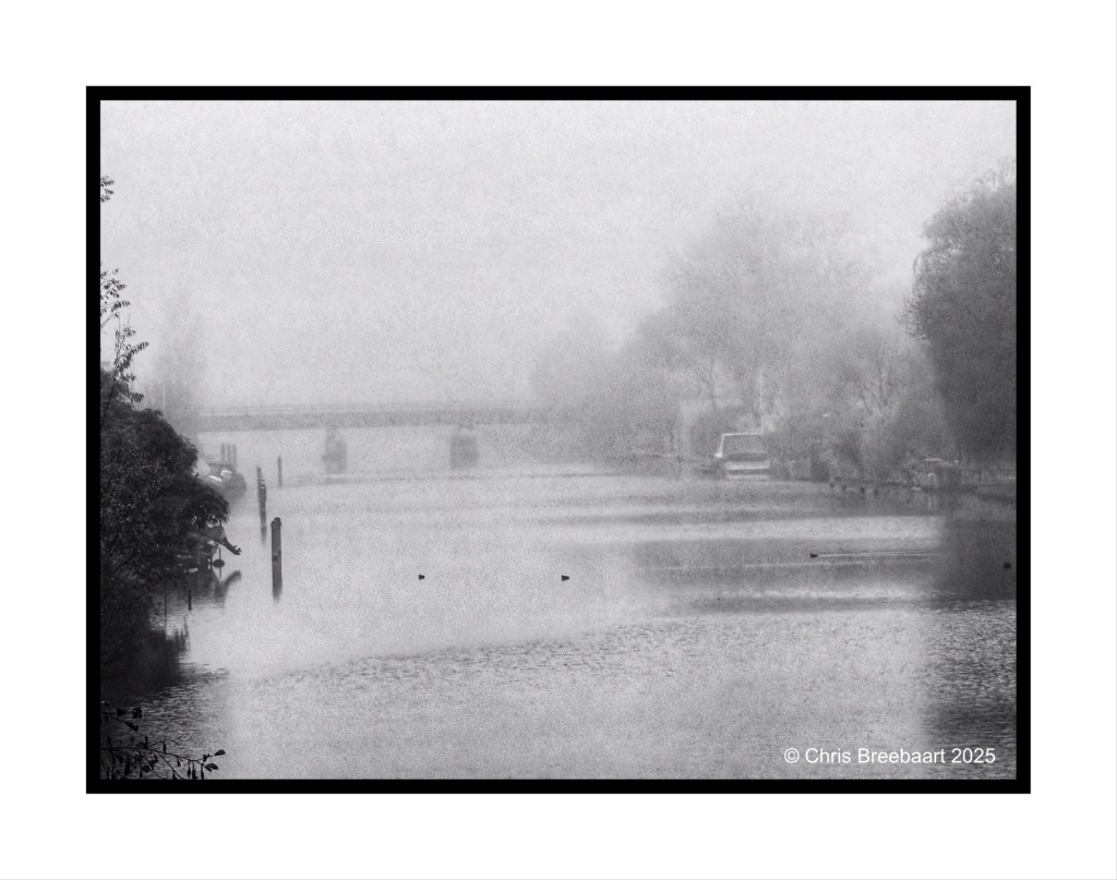 A foggy canal scene with a bridge in the background, surrounded by trees, reflecting a mysterious atmosphere.