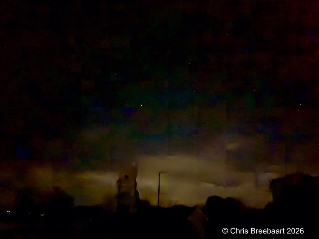A nighttime scene featuring dark clouds and a few visible stars, with silhouettes of buildings in the foreground.