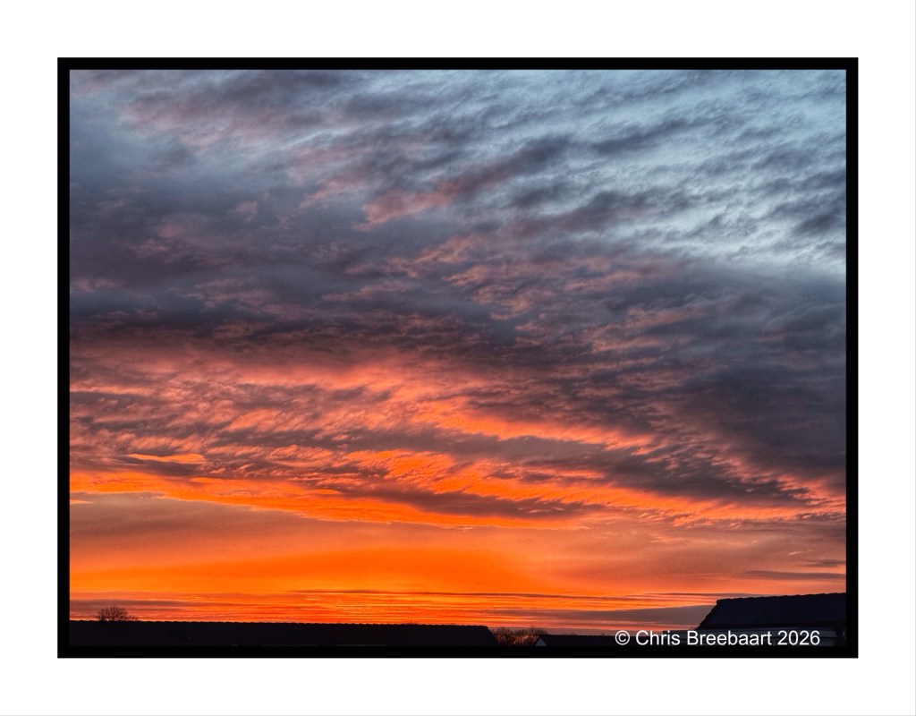 Vibrant sunset with orange and blue hues illuminating a cloudy sky.