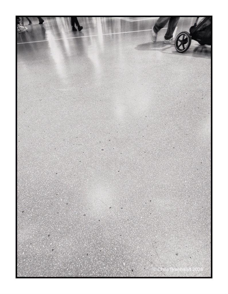 Close-up view of a smooth, polished floor with scattered light reflections and people walking in the background.