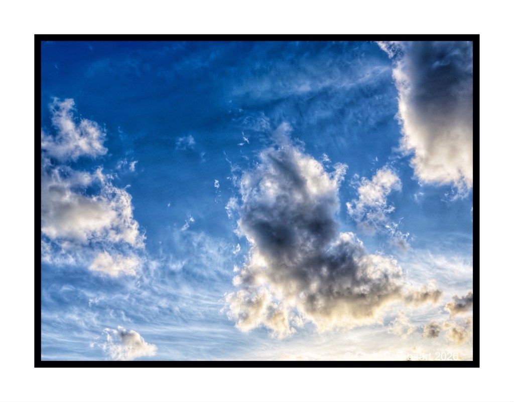 A bright blue sky filled with fluffy white clouds and wispy vapor trails.