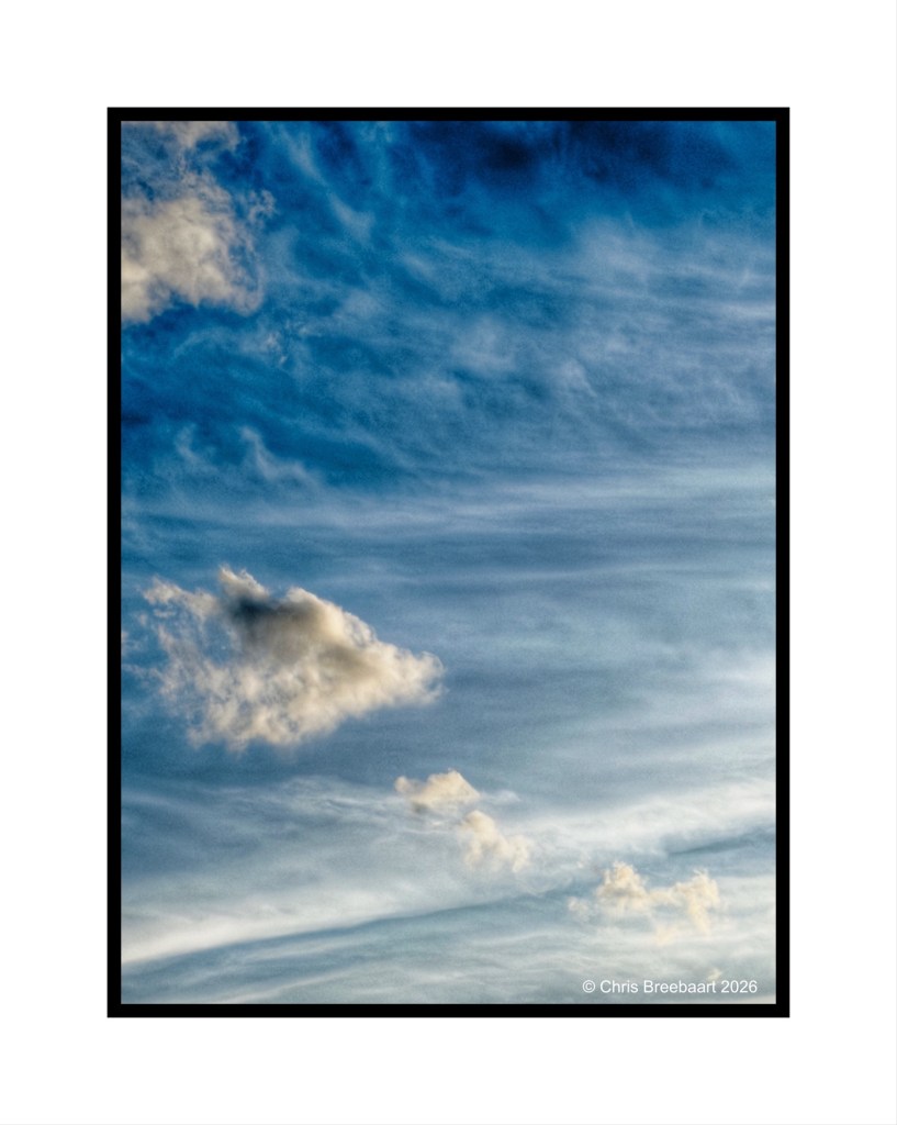 A serene sky featuring wispy clouds and a gradient of blue tones.