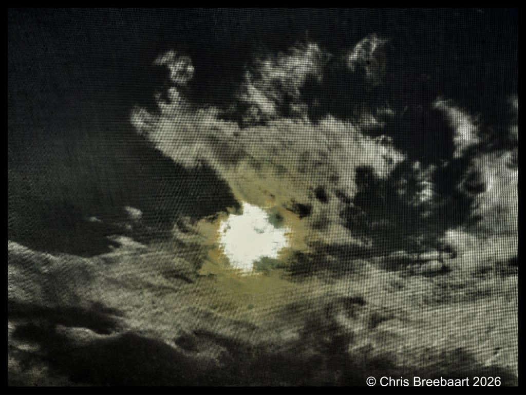 A dramatic sky filled with dark clouds and a bright opening revealing the sun, creating a contrast between light and shadows.