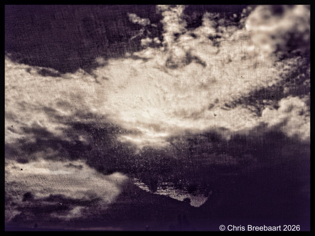 A dramatic, monochromatic image of a cloudy sky with varying cloud formations and light peeking through.