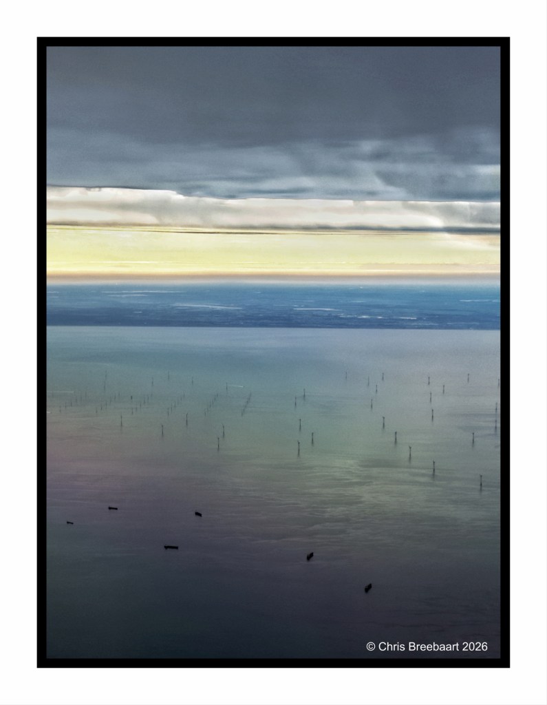 Aerial view of a calm body of water with multiple wind turbines in the distance, illuminated by a soft golden and blue gradient sky.
