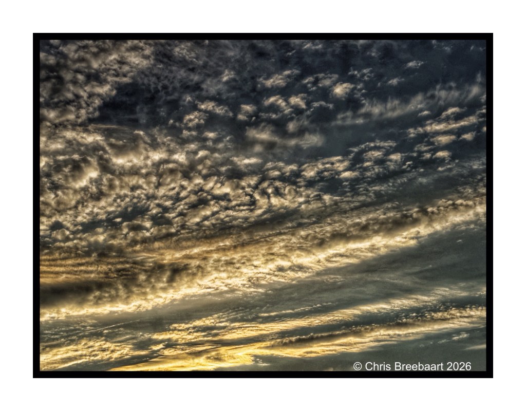 Dramatic clouds in a moody sky at sunset, featuring various shades of gray and hints of gold light.