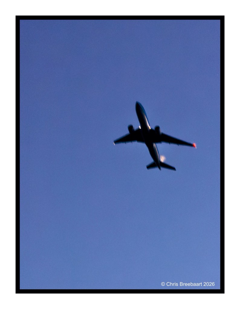 A plane flying against a clear blue sky.