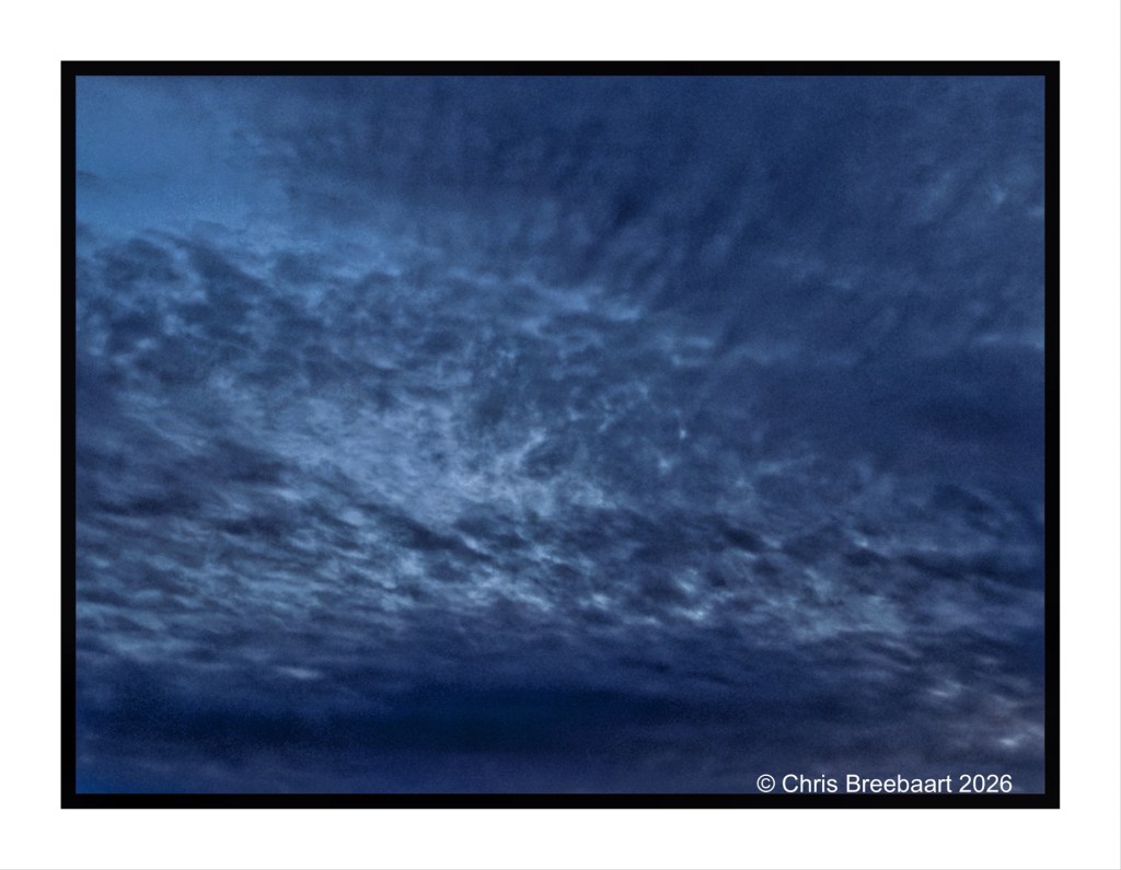 A dark sky filled with various shades of blue clouds, creating a textured and dramatic atmosphere.