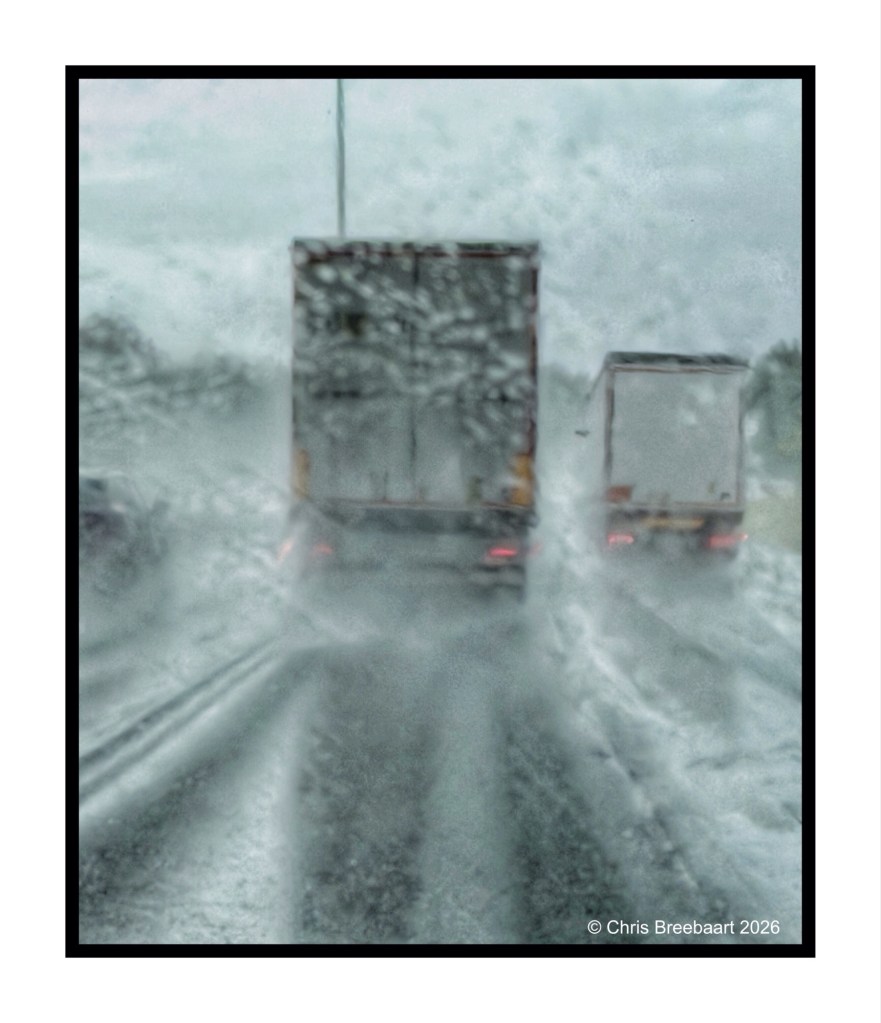 A blurred view of trucks on a snowy road, with heavy snowfall obscuring visibility.